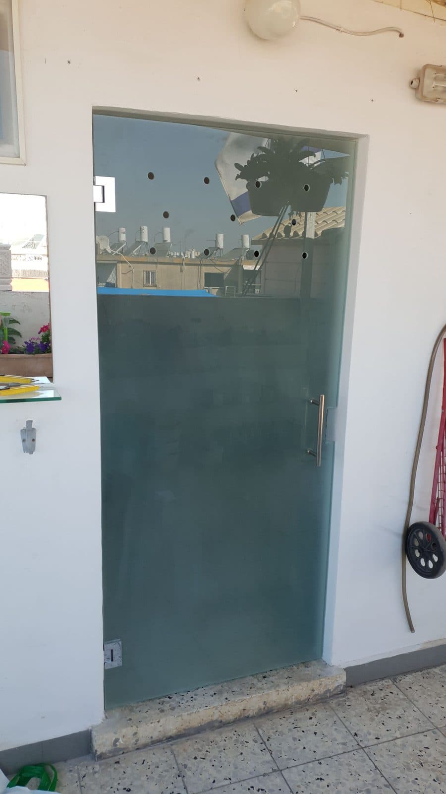 דלת זכוכית מחוספסת חלבית עם ידית נירוסטה מותקנת בקיר חוץ